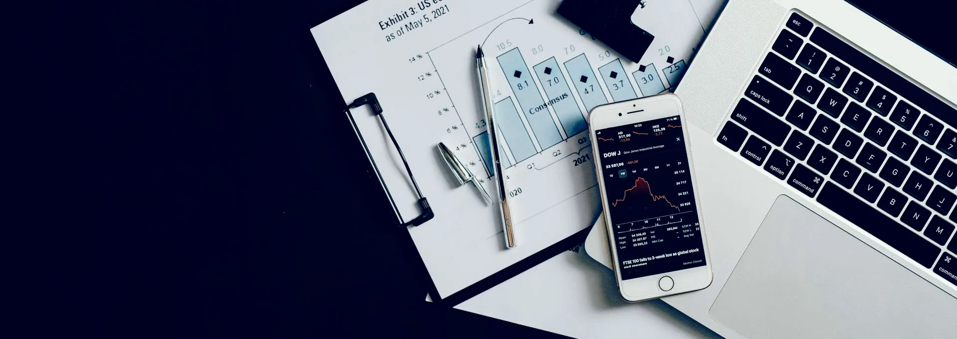 Laptop mit Datenanalyse neben ausgedruckten Tabellen